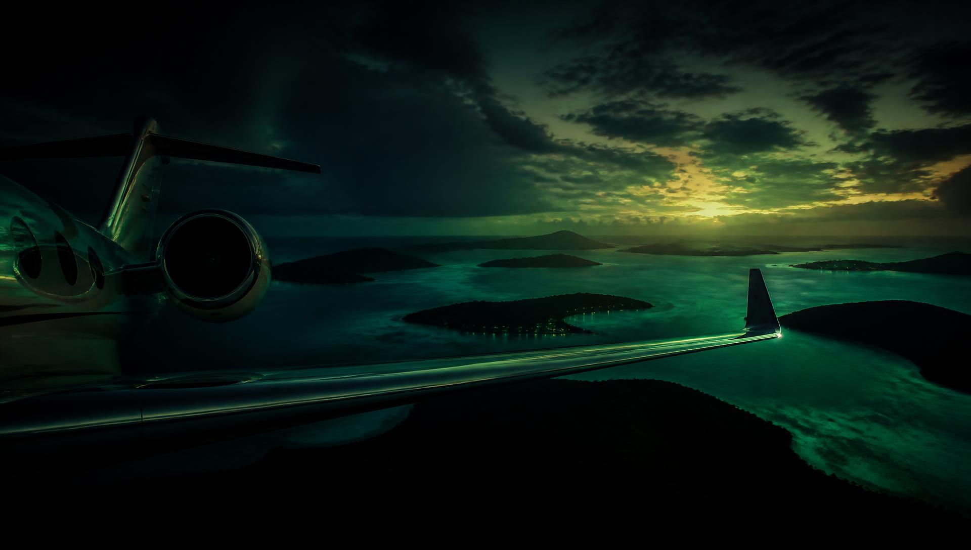 Private jet wing above tropical islands at dusk